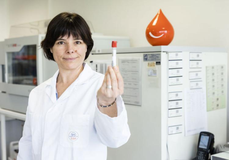 Un établissement régional disposant de nombreuses activités Technicienne de laboratoire tenant un tube d'analyse sanguine